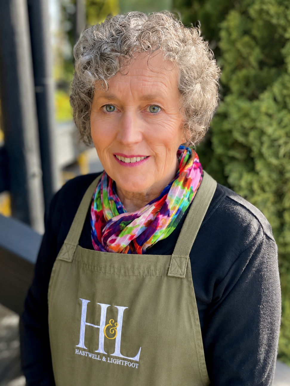 Person wearing a green apron with 'HL' logo, standing outdoors.